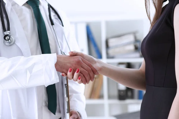 Doctor shake hand as hello with patient in office closeup