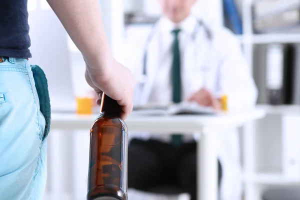 Alcoólico segurar na mão garrafa vazia na recepção do médico — Fotografia de Stock