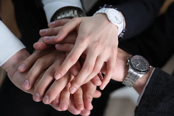 Group of people in suits crossed hands in pile