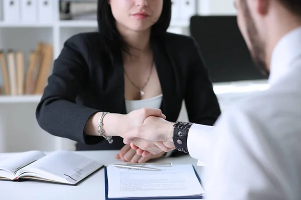 Businessman and woman shake hands as hello in office