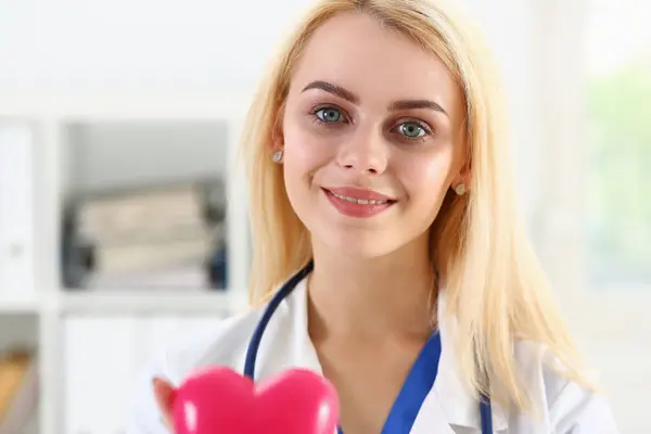Vrouwelijke geneeskunde arts houden in handen rood speelgoed hart — Stockfoto