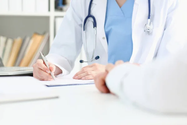 Lekarka ręka trzymać srebrne pióro wypełnienie listy pacjentów — Zdjęcie stockowe
