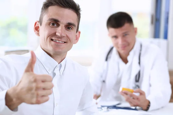 Hombre mostrando signo OK con el pulgar hacia arriba en el retrato del consultorio médico —  Fotos de Stock