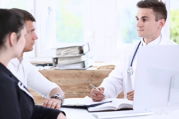 Médico de familia masculino escuchar cuidadosamente pareja joven en el consultorio — Foto de Stock