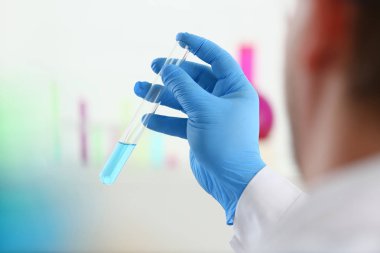 Bir erkek kimyager tüp cam onun el taşmaları tutar.