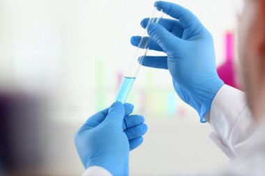 Bir erkek kimyager tüp cam onun el taşmaları tutar.