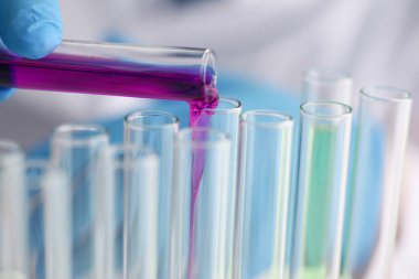 Bir erkek kimyager tüp cam onun el taşmaları tutar.