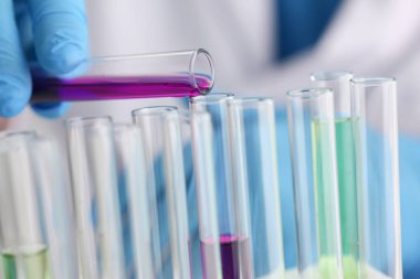 Bir erkek kimyager tüp cam onun el taşmaları tutar.