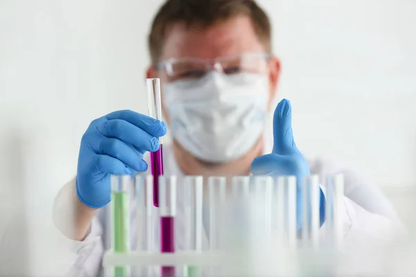 Un chimiste masculin tient un tube à essai de verre dans sa main débordements — Photo