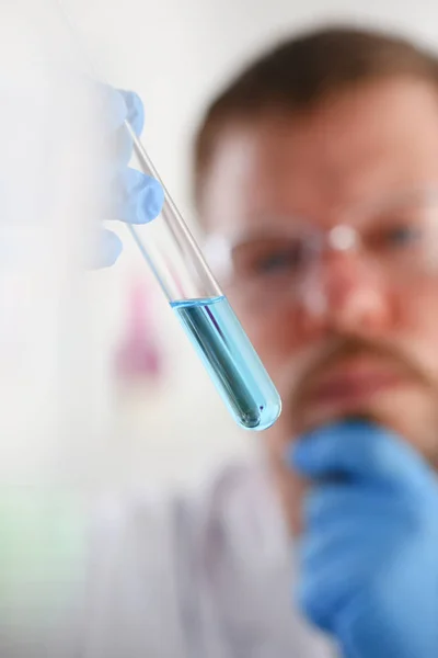 Un químico masculino sostiene tubo de ensayo de vidrio en su mano desborda — Foto de Stock