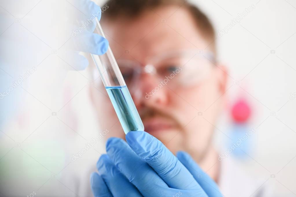 A male chemist holds test tube of glass in his hand overflows