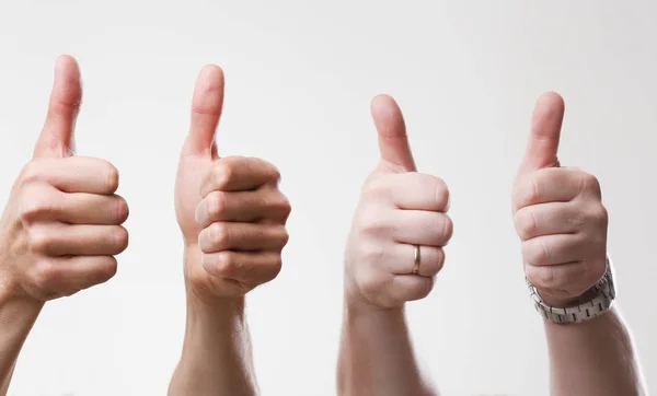 A group of people male hands on a gray background holds a thumb — Stock Photo, Image