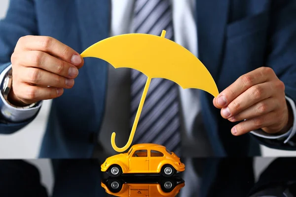 Brazo masculino en traje y corbata cubierta amarillo juguete coche — Foto de Stock