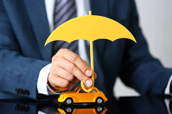 Male arm in suit and tie cover yellow toy car — Stock Photo, Image