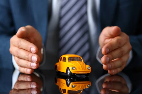 Braço masculino em terno e gravata tampa amarelo brinquedo carro — Fotografia de Stock