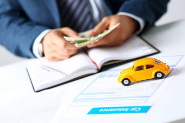 Masanın üzerinde yatan sarı oyuncak araba ile sigorta formu