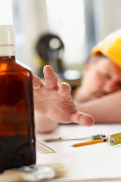 Arm of drunken worker in yellow helmet