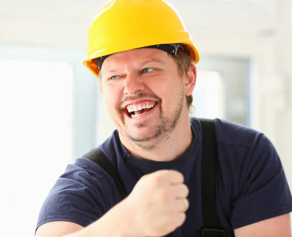 Χαμογελώντας αστεία εργαζόμενος σε κίτρινο κράνος που παρουσιάζουν — Φωτογραφία Αρχείου