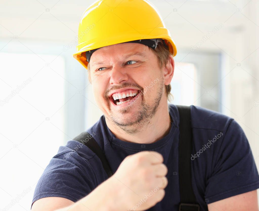 Smiling funny worker in yellow helmet posing