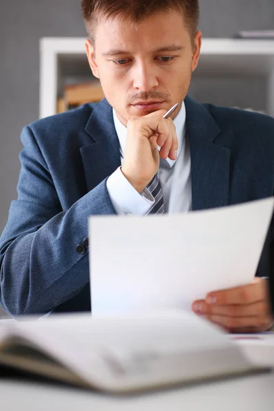 Uomo d'affari serio in ufficio esamina i documenti — Foto Stock