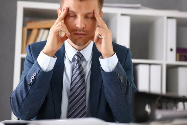 Um homem experimenta estresse e dor de cabeça no local de trabalho — Fotografia de Stock