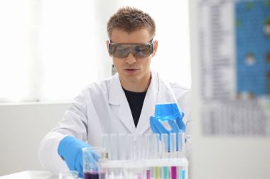 Bir erkek kimyager tüp elinde bardak sıvı bir çözüm taşmaları tutar