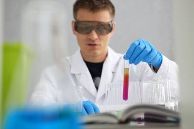 Bir erkek kimyager tüp elinde bardak sıvı bir çözüm taşmaları tutar