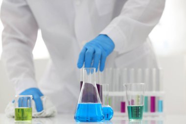 Bir erkek kimyager tüp elinde bardak sıvı bir çözüm taşmaları tutar