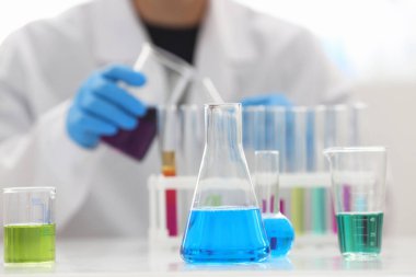 Bir erkek kimyager tüp elinde bardak sıvı bir çözüm taşmaları tutar