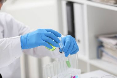 Bir erkek kimyager tüp elinde bardak sıvı bir çözüm taşmaları tutar