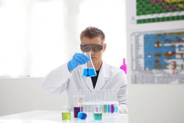 Bir erkek kimyager tüp elinde bardak sıvı bir çözüm taşmaları tutar