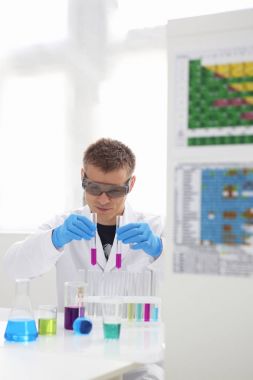 Bir erkek kimyager tüp elinde bardak sıvı bir çözüm taşmaları tutar