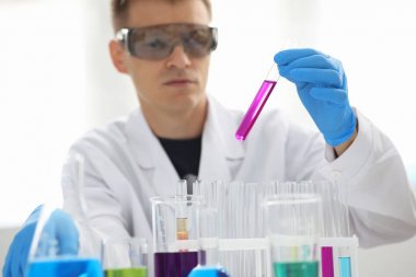 Bir erkek kimyager tüp elinde bardak sıvı bir çözüm taşmaları tutar