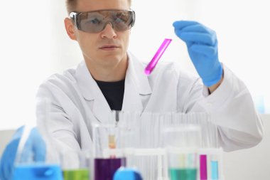 Bir erkek kimyager tüp elinde bardak sıvı bir çözüm taşmaları tutar