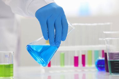 Bir erkek kimyager tüp elinde bardak sıvı bir çözüm taşmaları tutar