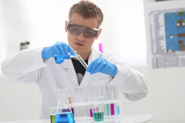 Bir erkek kimyager tüp elinde bardak sıvı bir çözüm taşmaları tutar