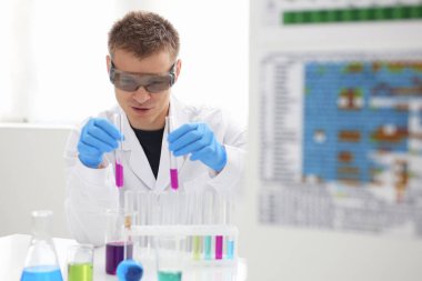 Bir erkek kimyager tüp elinde bardak sıvı bir çözüm taşmaları tutar