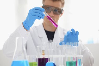 Bir erkek kimyager tüp elinde bardak sıvı bir çözüm taşmaları tutar