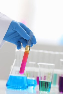 Bir erkek kimyager tüp elinde bardak sıvı bir çözüm taşmaları tutar