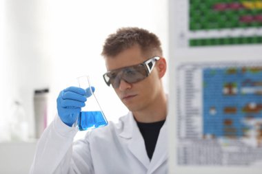 Bir erkek kimyager tüp elinde bardak sıvı bir çözüm taşmaları tutar