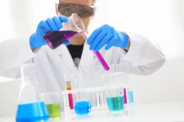Ein Chemiker hält ein Reagenzglas in der Hand und übergießt eine flüssige Lösung — Stockfoto
