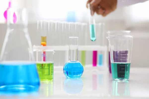 Ampoule de l'industrie chimique avec tube à essai liquide rose magenta bleu sur la table — Photo