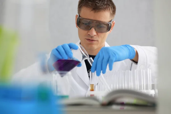 Mužské chemik drží zkumavky skla v ruce přetečení kapalného roztoku — Stock fotografie