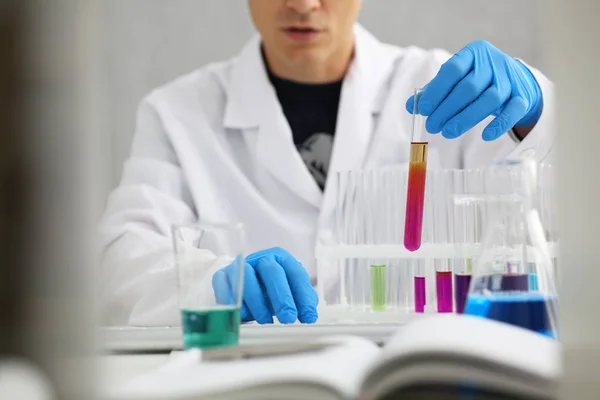 Ένα αρσενικό χημικός κατέχει δοκιμαστικό σωλήνα από γυαλί με το χέρι ξεχειλίζει υγρό διάλυμα — Φωτογραφία Αρχείου