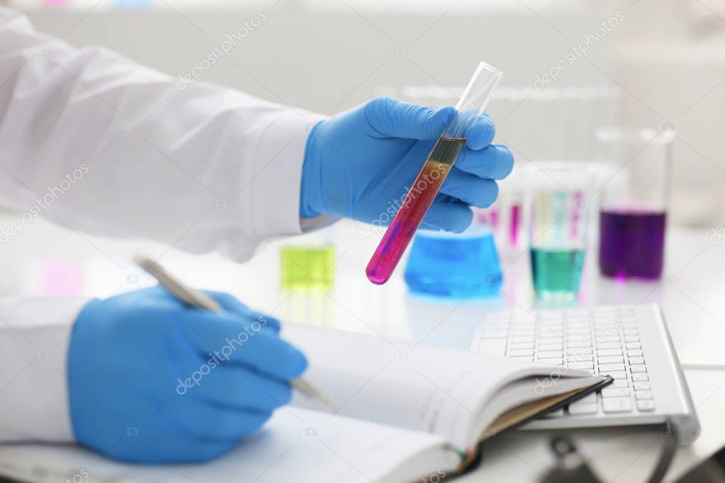 Employee of the chemical laboratory teacher chemist holds a silvery pen 