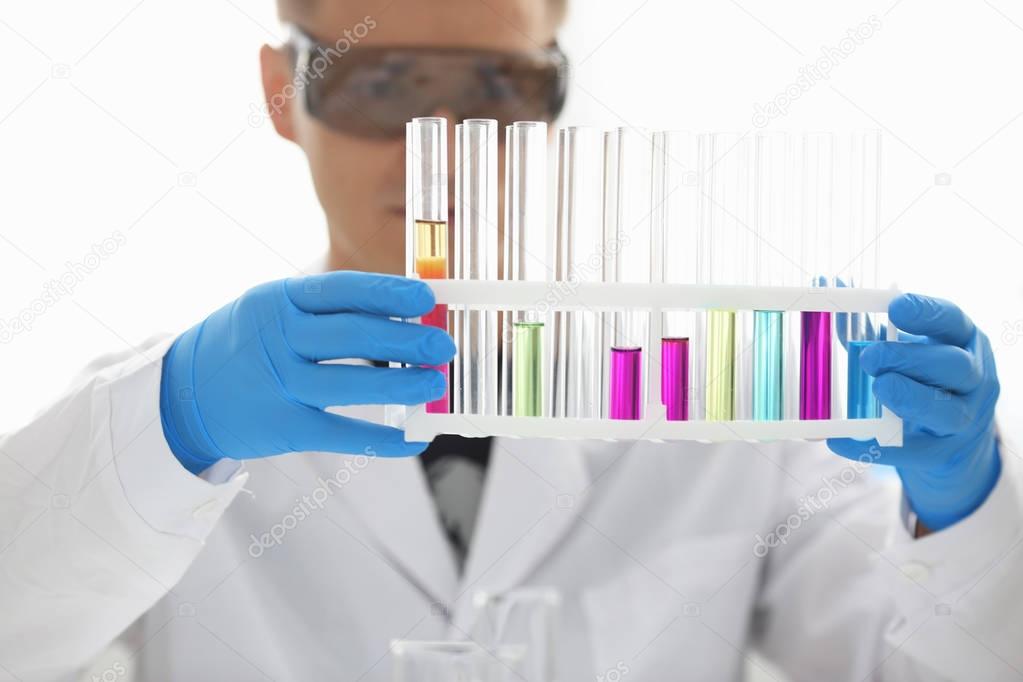 A male chemist holds test tube of glass in his hand overflows a liquid solution