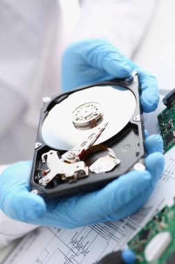 Erkek tamirci mavi eldiven giymiş bir sabit disk tutuyor