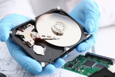 Erkek tamirci mavi eldiven giymiş bir sabit disk tutuyor