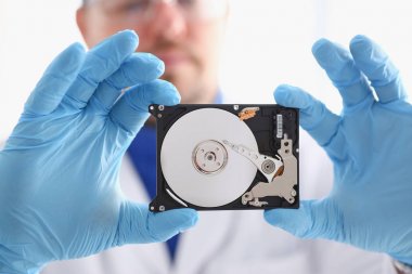 Erkek tamirci mavi eldiven giymiş bir sabit disk tutuyor