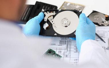 Erkek tamirci mavi eldiven giymiş bir sabit disk tutuyor